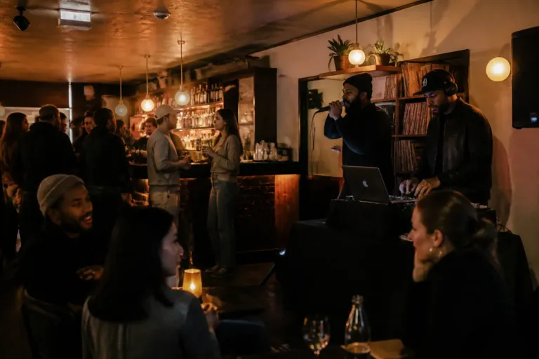 dj and mc duo on a small stage while guests mingle and talk in a cozy lounge bar